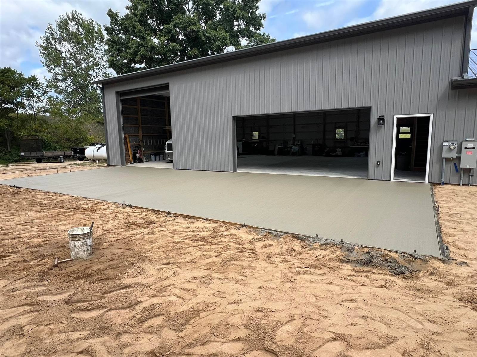 Large concrete apron poured in front of a gray pole barn