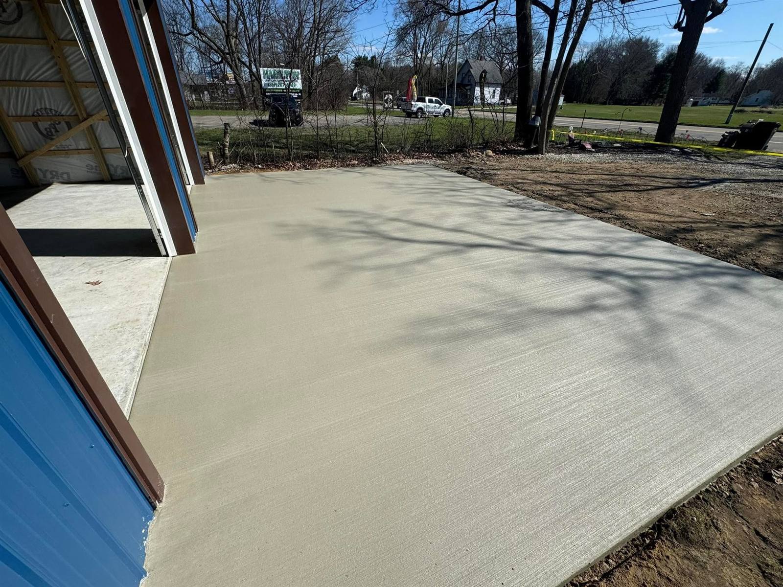 Fresh broom-finished slab outside a pole barn