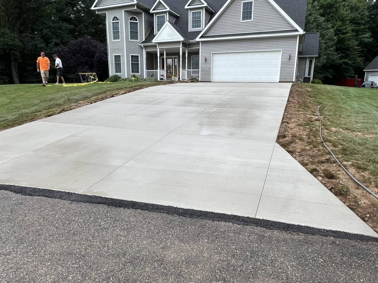 New concrete driveway leading up to a two-story home
