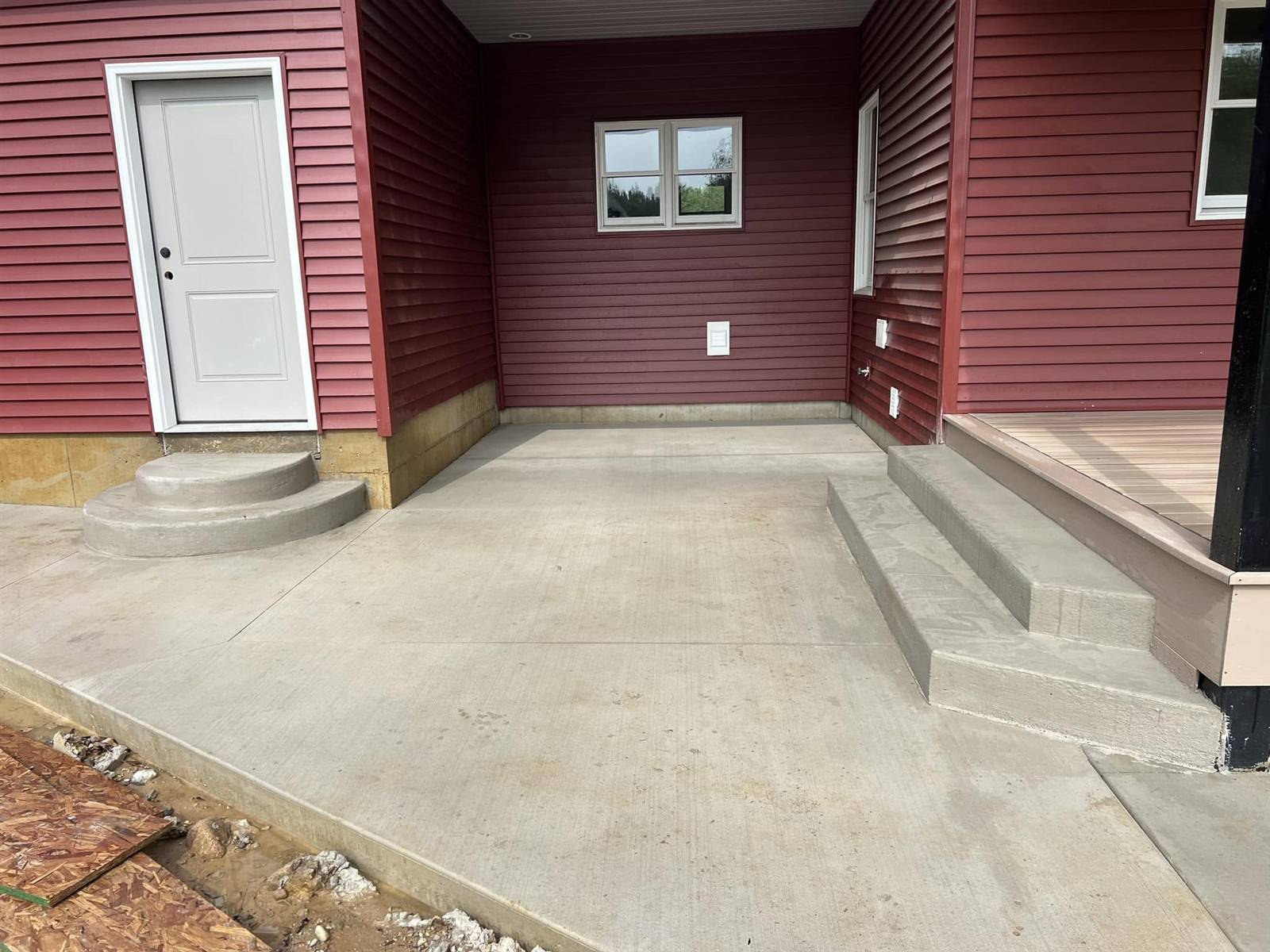 Back patio with rounded concrete steps at a red-sided house